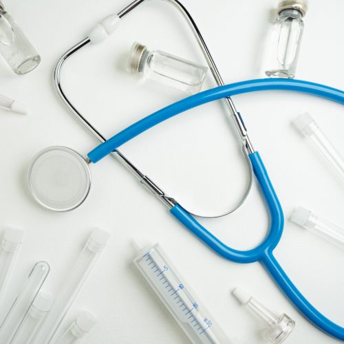 medical-layout-white-table-flat-lay-blue-stethoscope-phonendoscope-surrounded-by-vials-ampoules-test-tubes